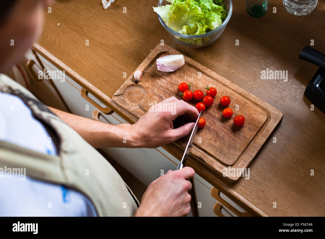 Uomo insalata di cottura in cucina, maschio mani il taglio di pomodori, cibo sano Foto Stock