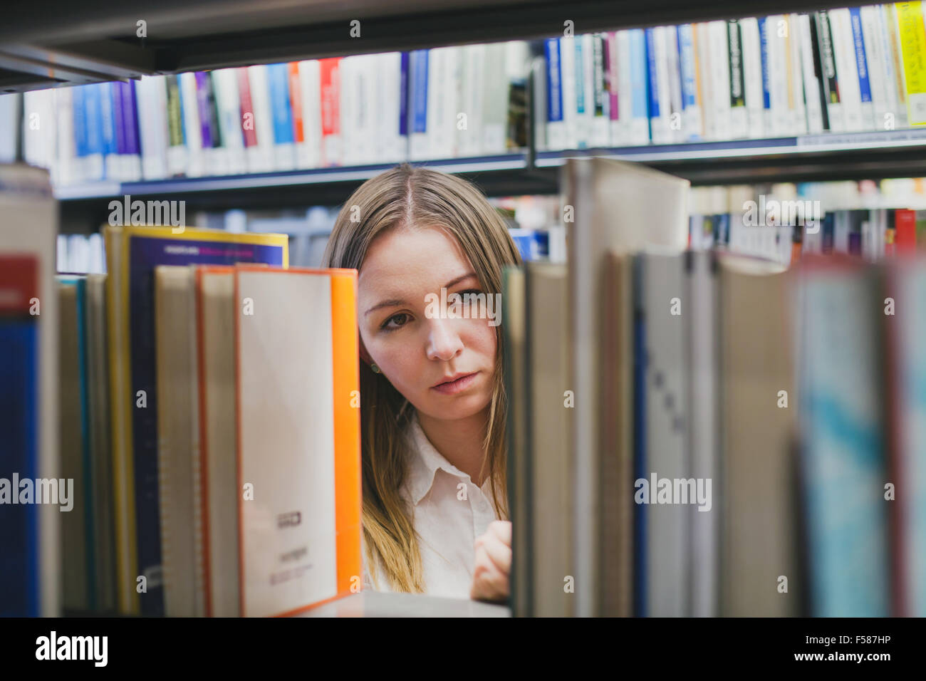 Una studentessa scegliendo libro in biblioteca Foto Stock