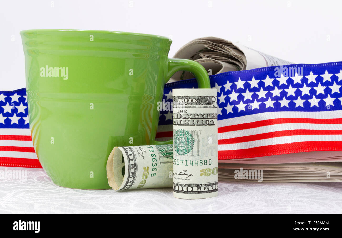 Moneta americana poste nella parte anteriore del giornale, bandiera nastro design e verde mug sulla biancheria da letto bianca. Foto Stock