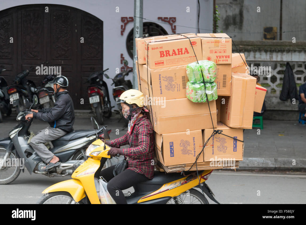 Donna vietnamita su uno scooter moto portando grande carico di scatole di cartone attraverso Hanoi centro,Vietnam,asia Foto Stock