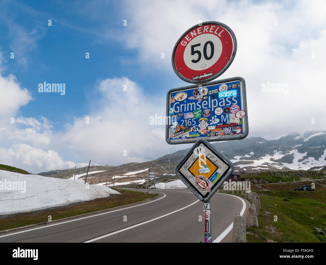 Strada segno sulla sommità del Grimsel Swiss mountain pass road (altitudine 2165m), incollati con adesivi di bypassare i turisti. Foto Stock