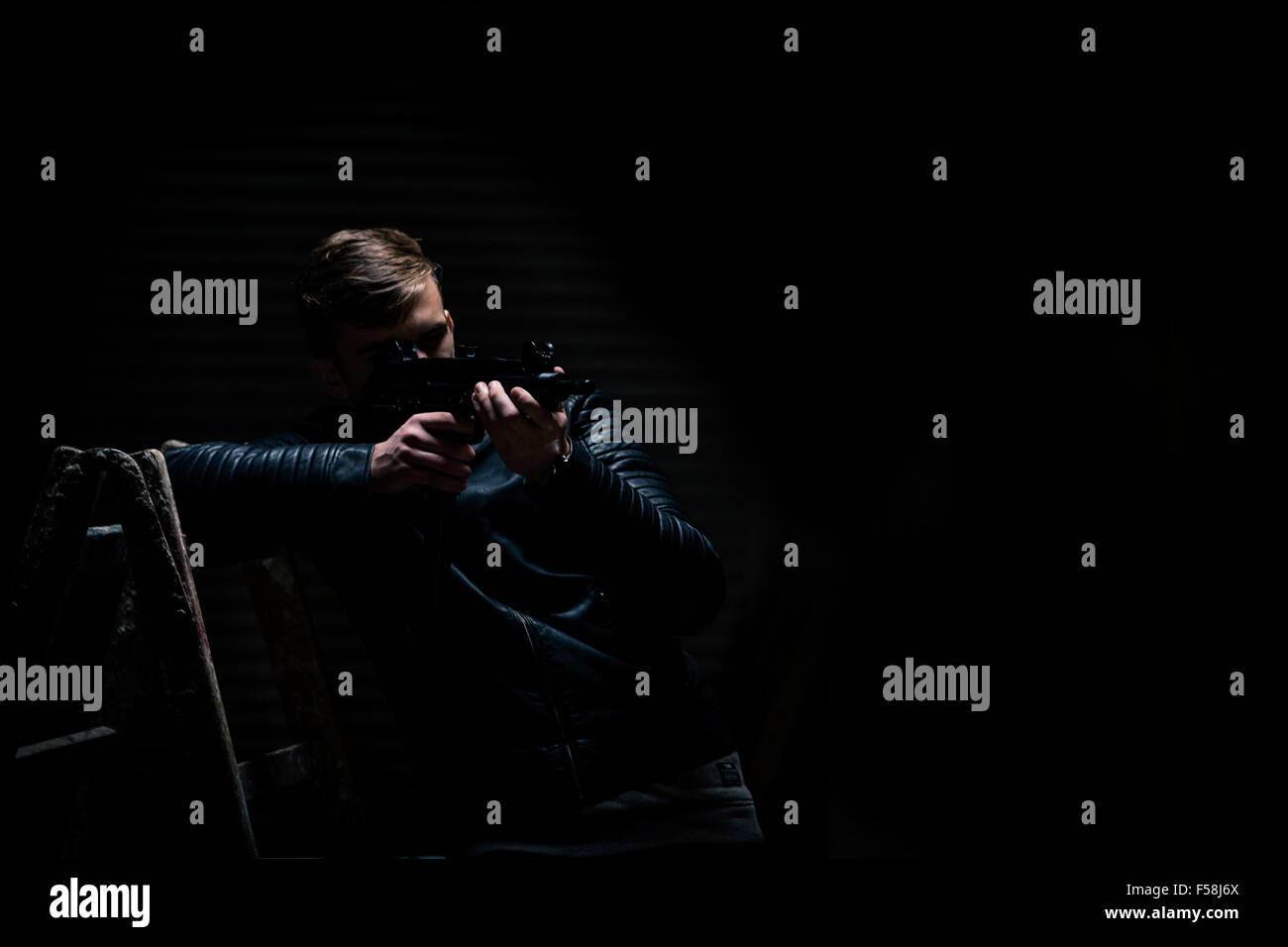 Giovane uomo punti un trapano elettrico come se si trattasse di una pistola. medium shot. Foto Stock