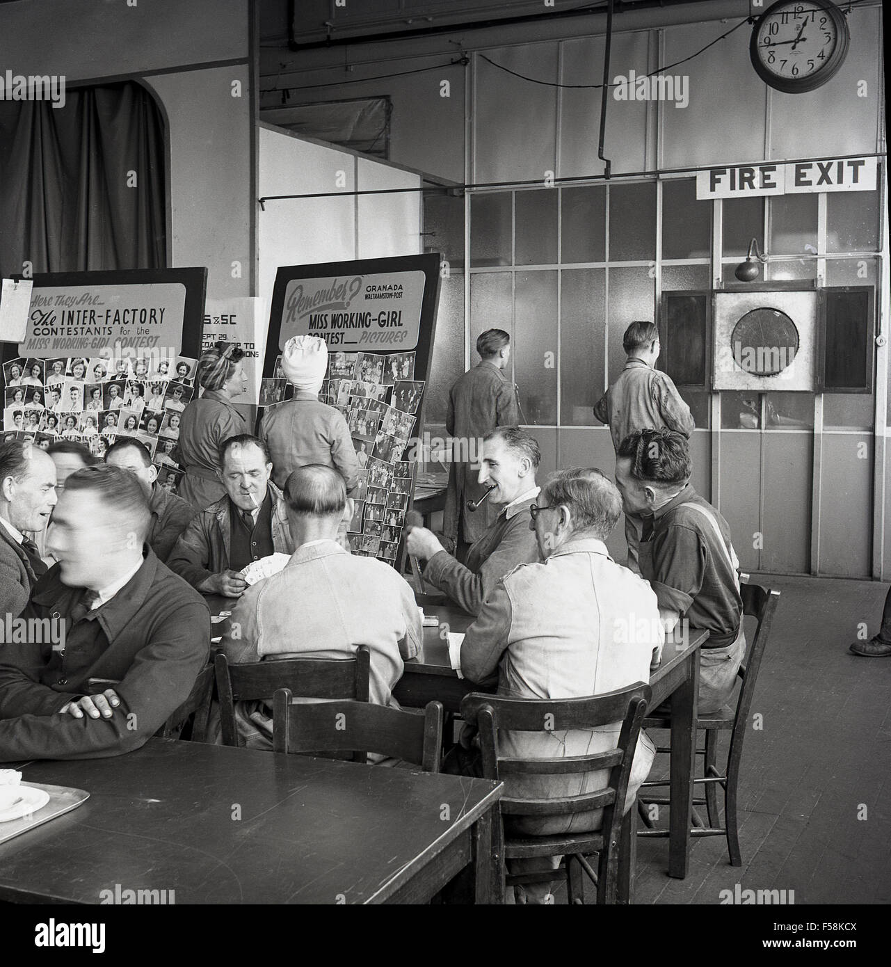 Anni Cinquanta foto storiche dei lavoratori in fabbrica avente un tea break del personale in sala di riposo, alcune carte da gioco, altri freccette. I lavoratori di sesso femminile guardare al consiglio di amministrazione che mostra le immagini di Miss Working-Girl contest. Foto Stock