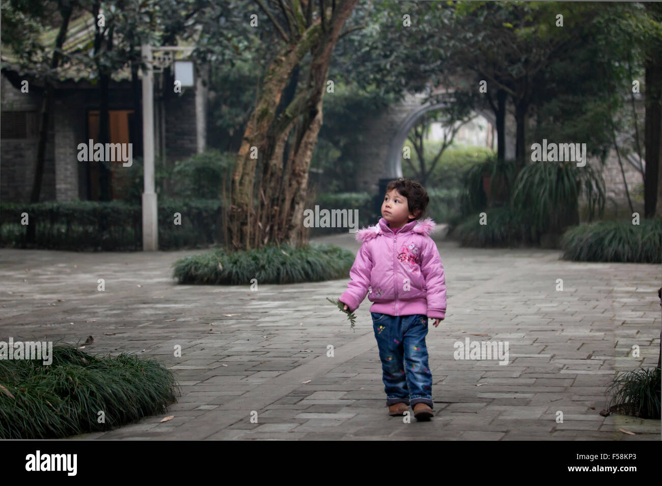 Una ragazzina di esplorare un vecchio giardino di una vecchia chiamata Gucheng in Pixian alla periferia di Chengdu in Cina. Foto Stock