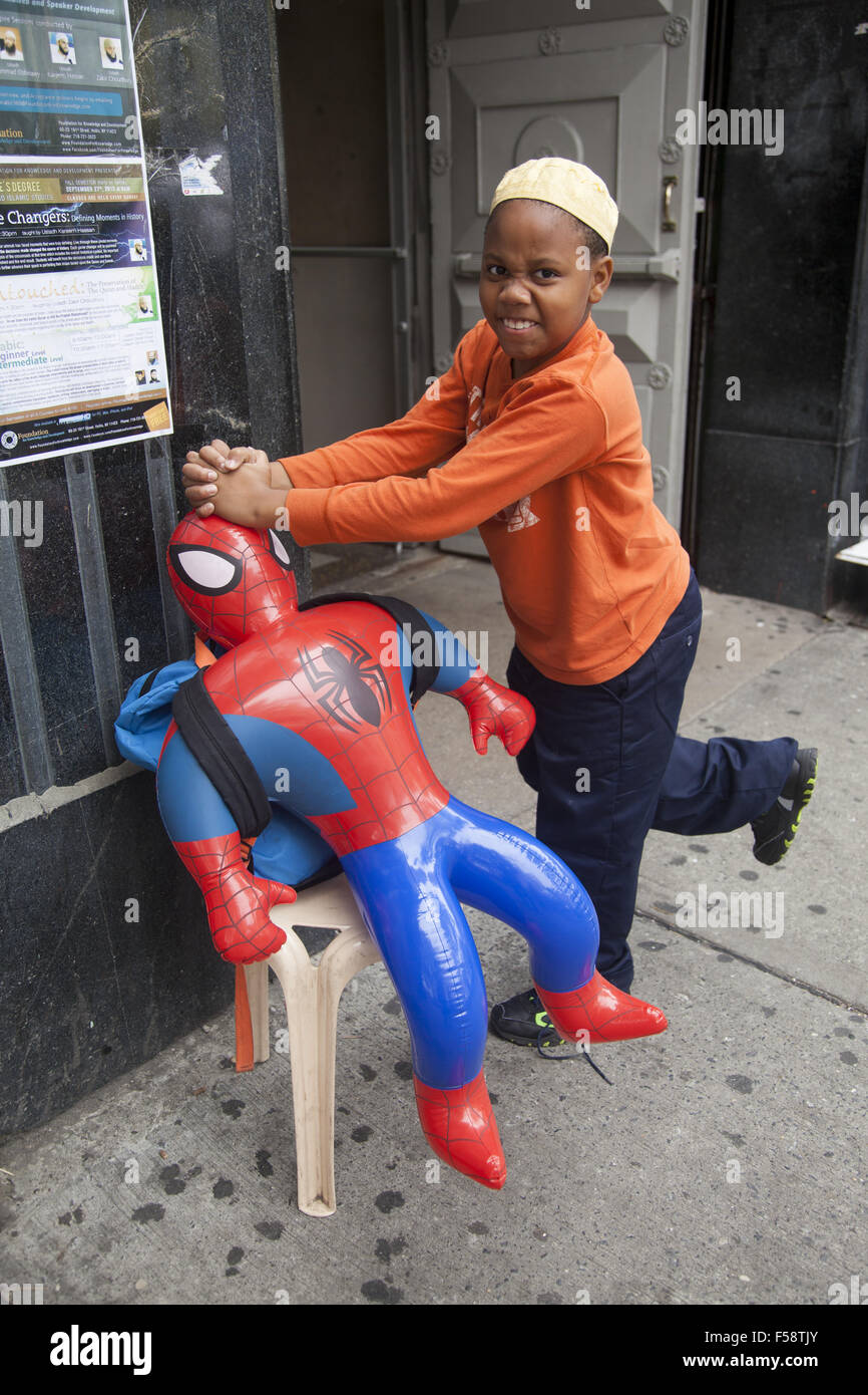 Giovane ragazzo musulmano dando a Spider-Man sulla Street in Brooklyn, New York. Foto Stock