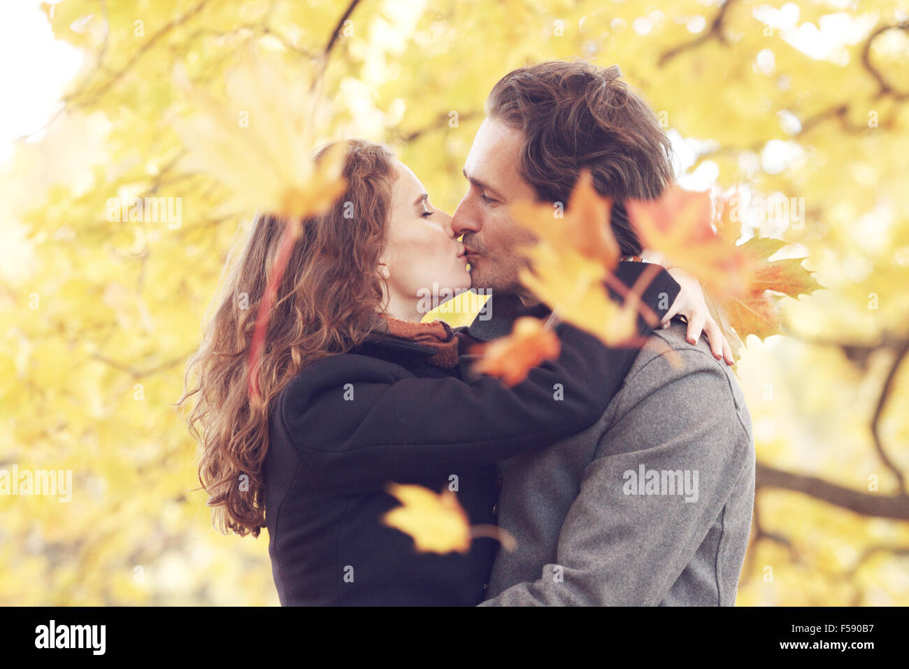 Bella giovane con foglie di acero baciare in autunno park Foto Stock