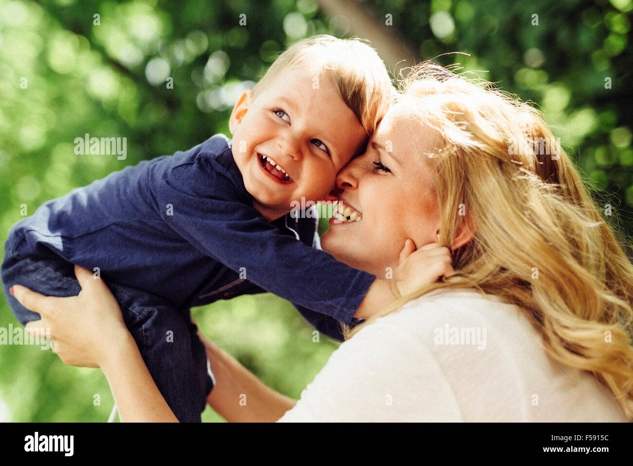 Madre sorridente ridendo e giocando con il suo bambino all'aperto su un bel giorno di estate Foto Stock