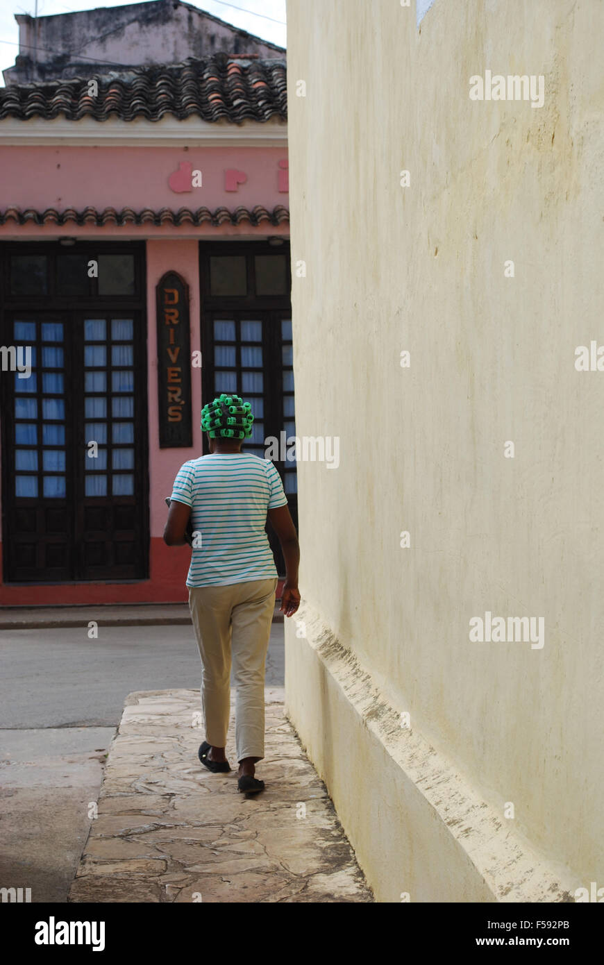 Una donna cubana in arricciacapelli a piedi lungo una strada di Remedios, Cuba Foto Stock