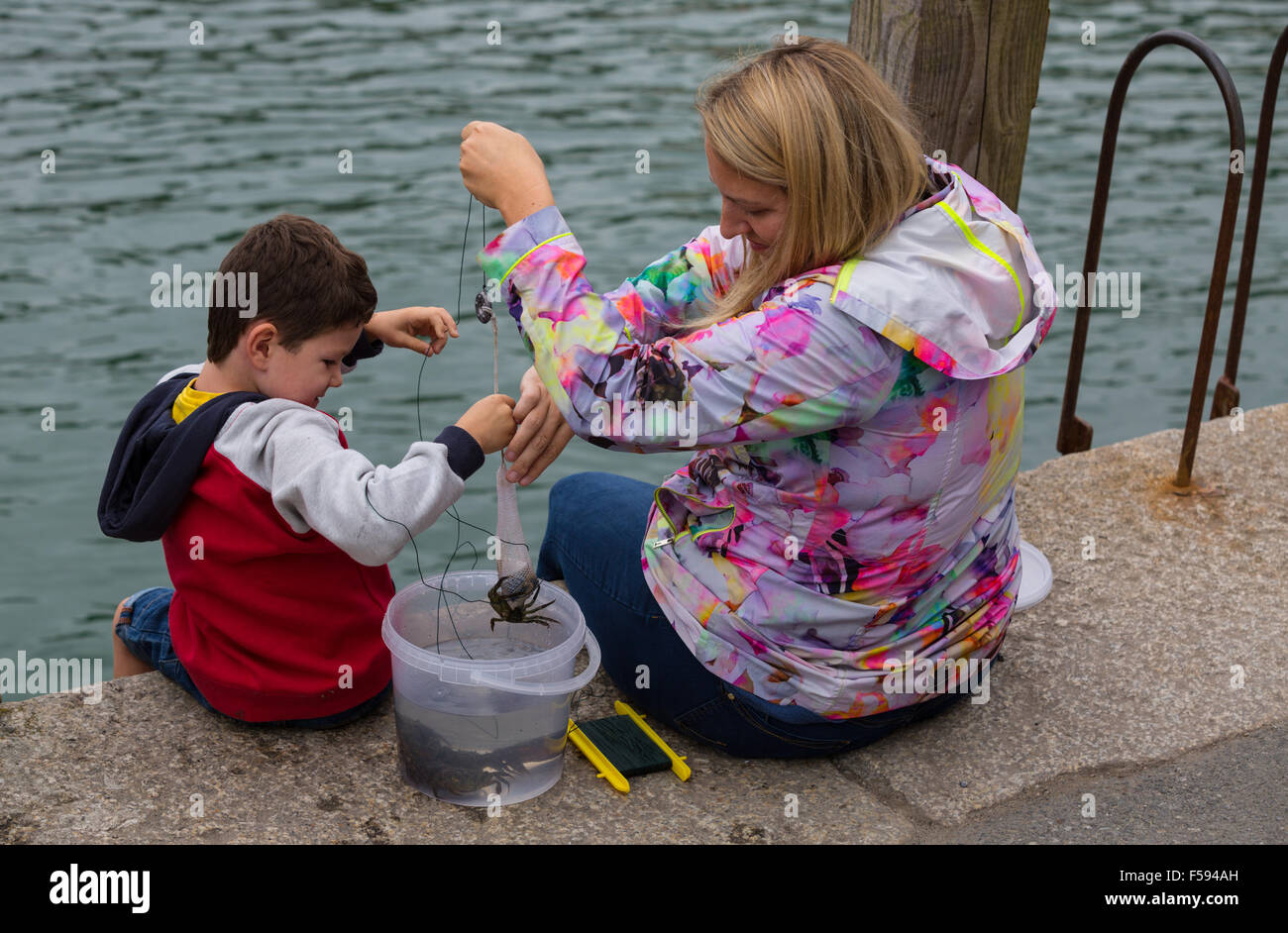 Madre e Figlio la pesca dei granchi nel porto di Looe Foto Stock