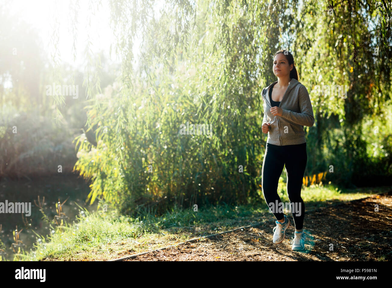 Ragazza sportiva jogging nel parco vicino a un fiume Foto Stock