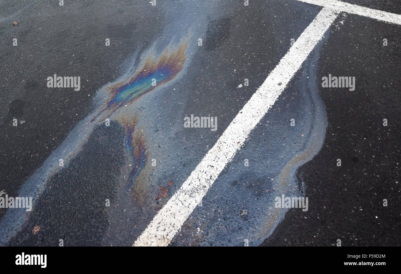 Fuoriuscita di olio su asfalto scuro, parcheggio con linee divisorie Foto Stock
