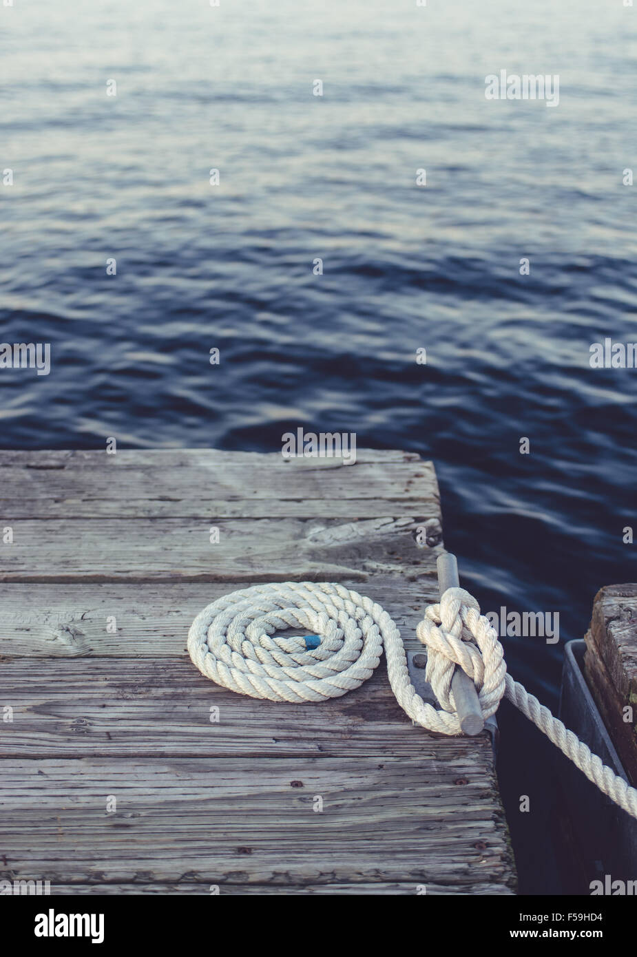 Cima nautica perfettamente avvolto e avvolto su un vecchio weathered dock. Foto Stock