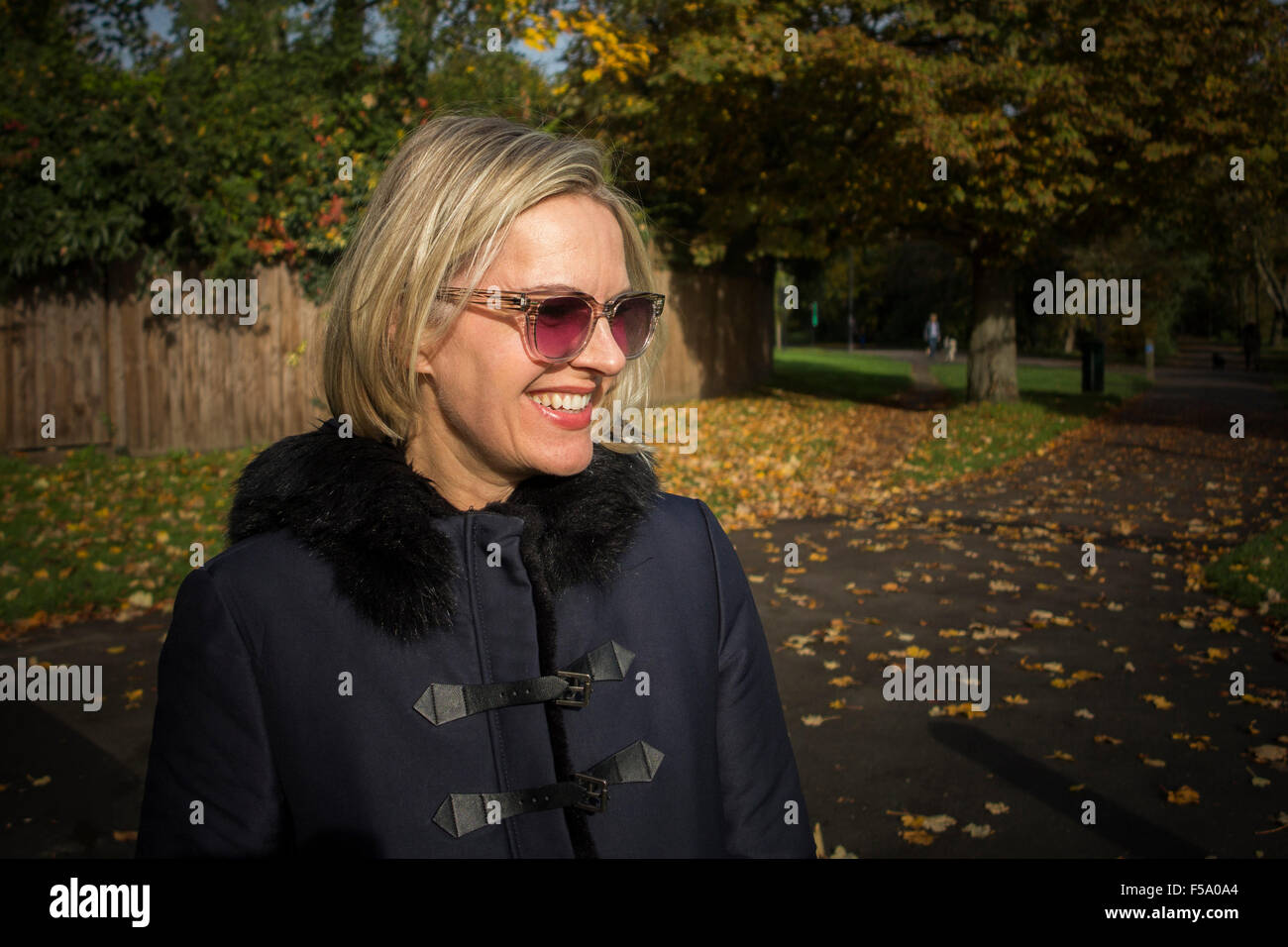 Gode di una donna il sole autunnale su una passeggiata in un parco di Londra Foto Stock Gode di una donna il sole autunnale su una passeggiata in un parco di Londra Foto Stock