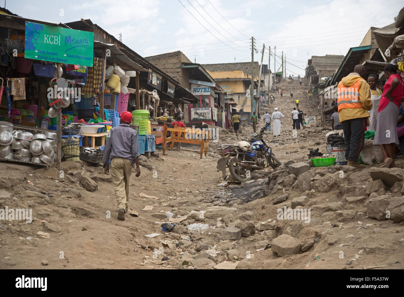 Le persone e i negozi a ruvida strada rocciosa Kamere bidonville Naivasha Kenya Foto Stock