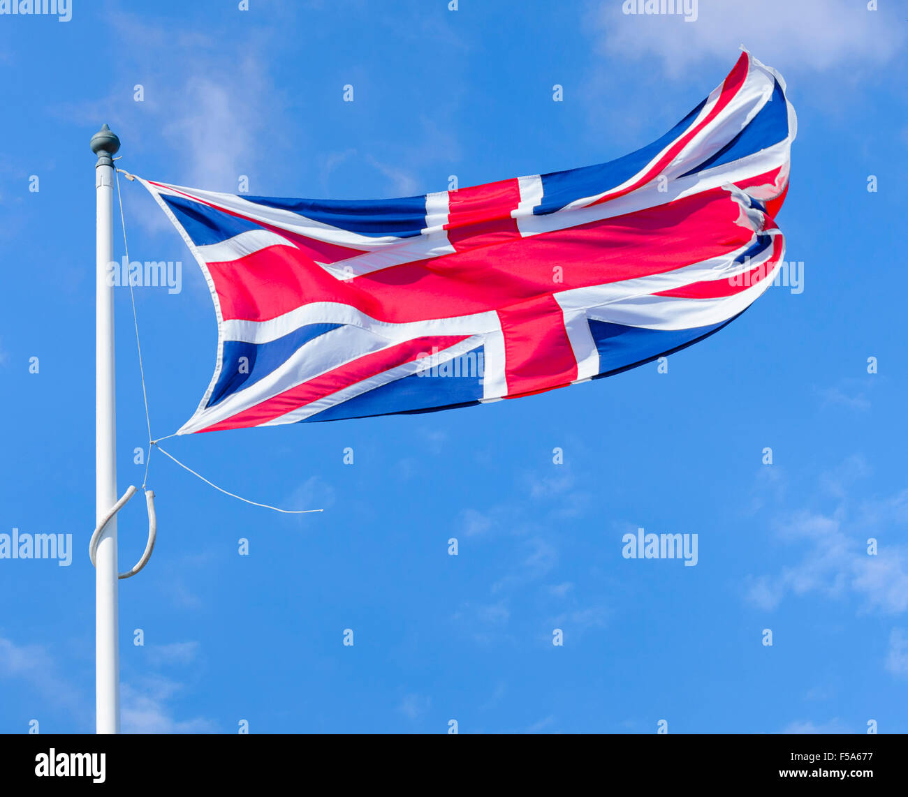Union Jack, bandiera del Regno Unito di Gran Bretagna e Irlanda del Nord, volare su un palo contro il cielo blu. Foto Stock