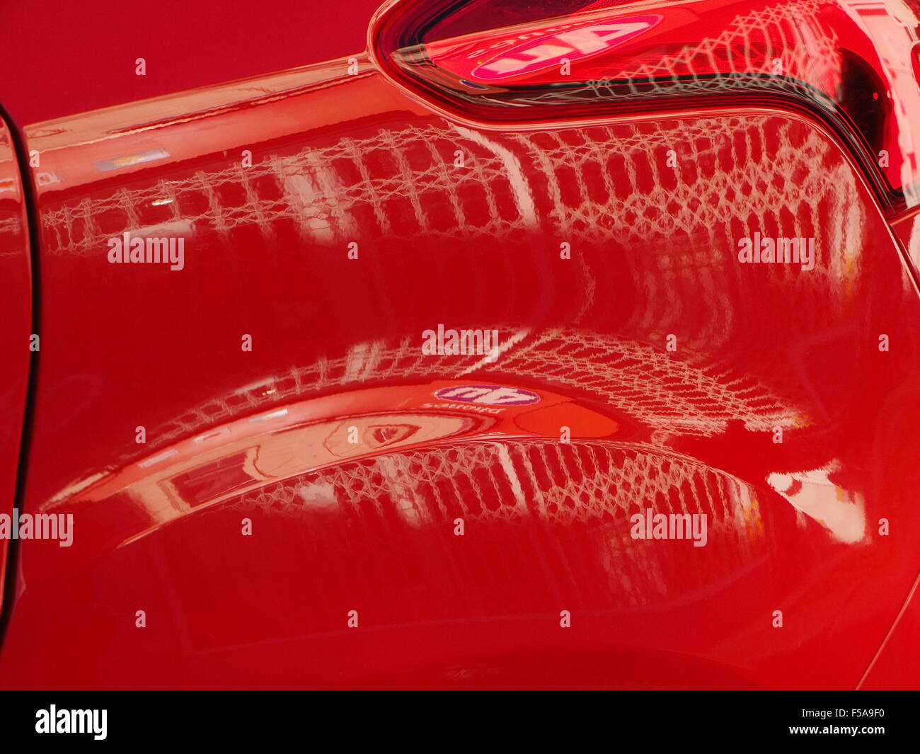 Shiny bright auto rossa del pannello del parafango posteriore e luce cluster con riflessioni di griglie bianco distorta da curve creazione di immagine grafica Foto Stock