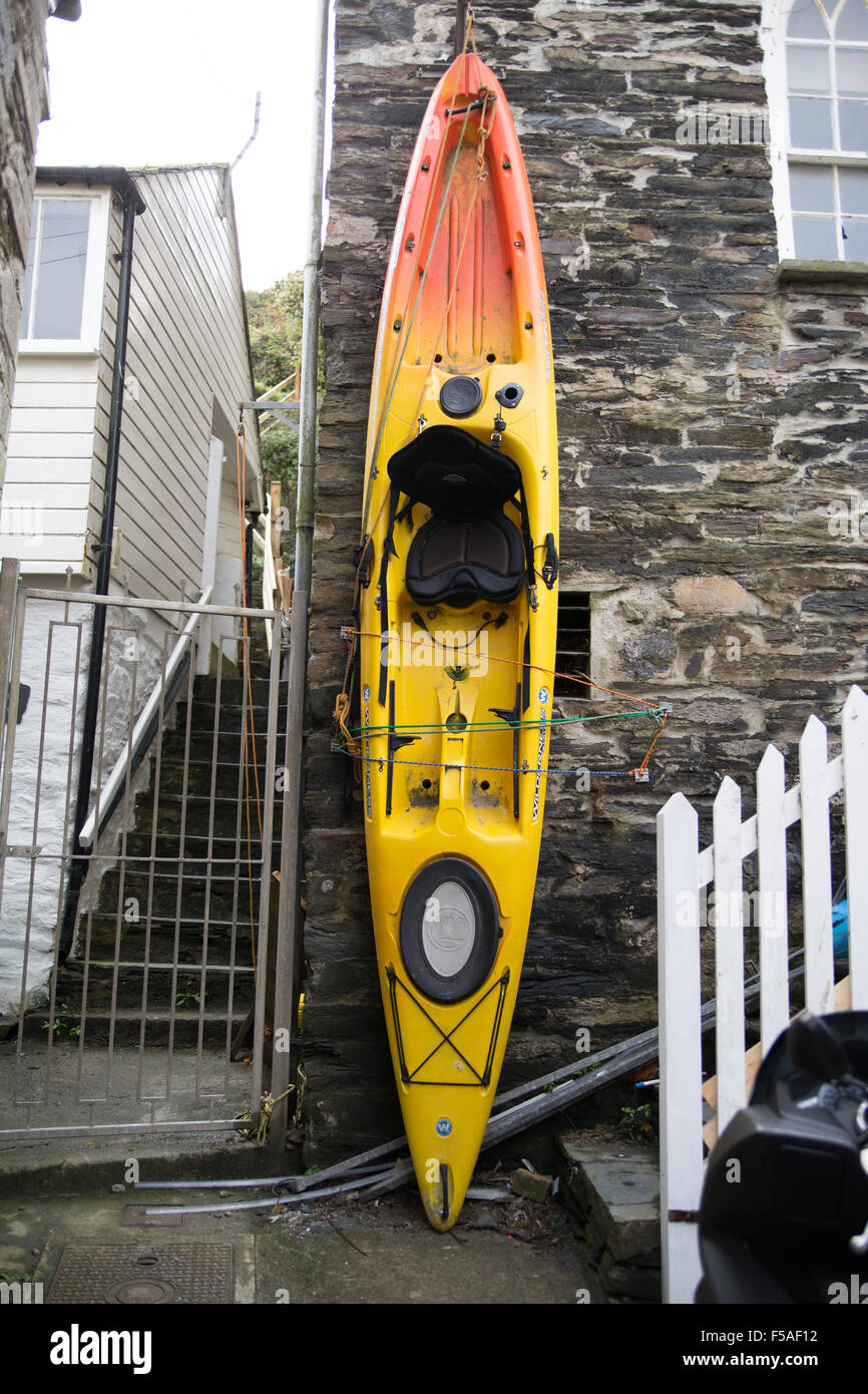 Una canoa immagazzinate verticalmente contro un muro in Port Isaac. Foto Stock