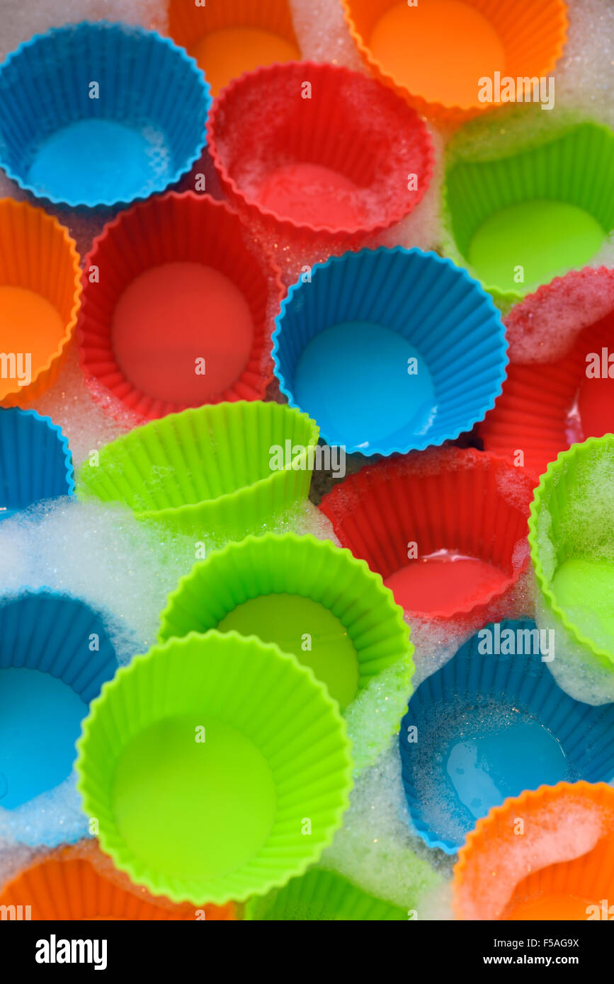 Silicone colorate con bicchieri di plastica per rendere i tortini con acqua saponata Foto Stock