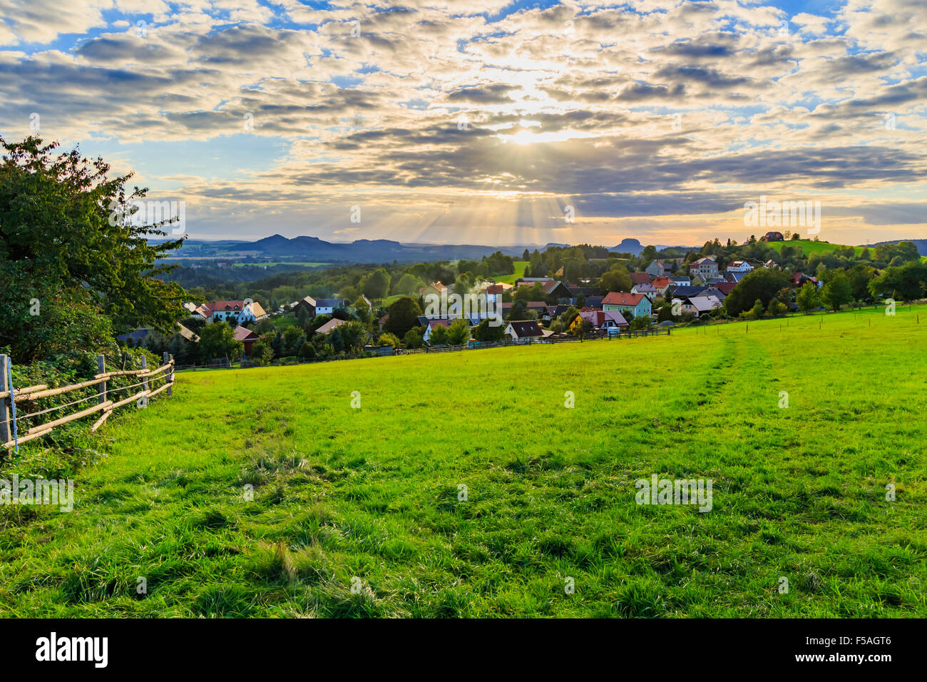 Bel tramonto su campagna paesaggio di dolci colline con raggi di sole cielo di perforazione e la collina di illuminazione Foto Stock