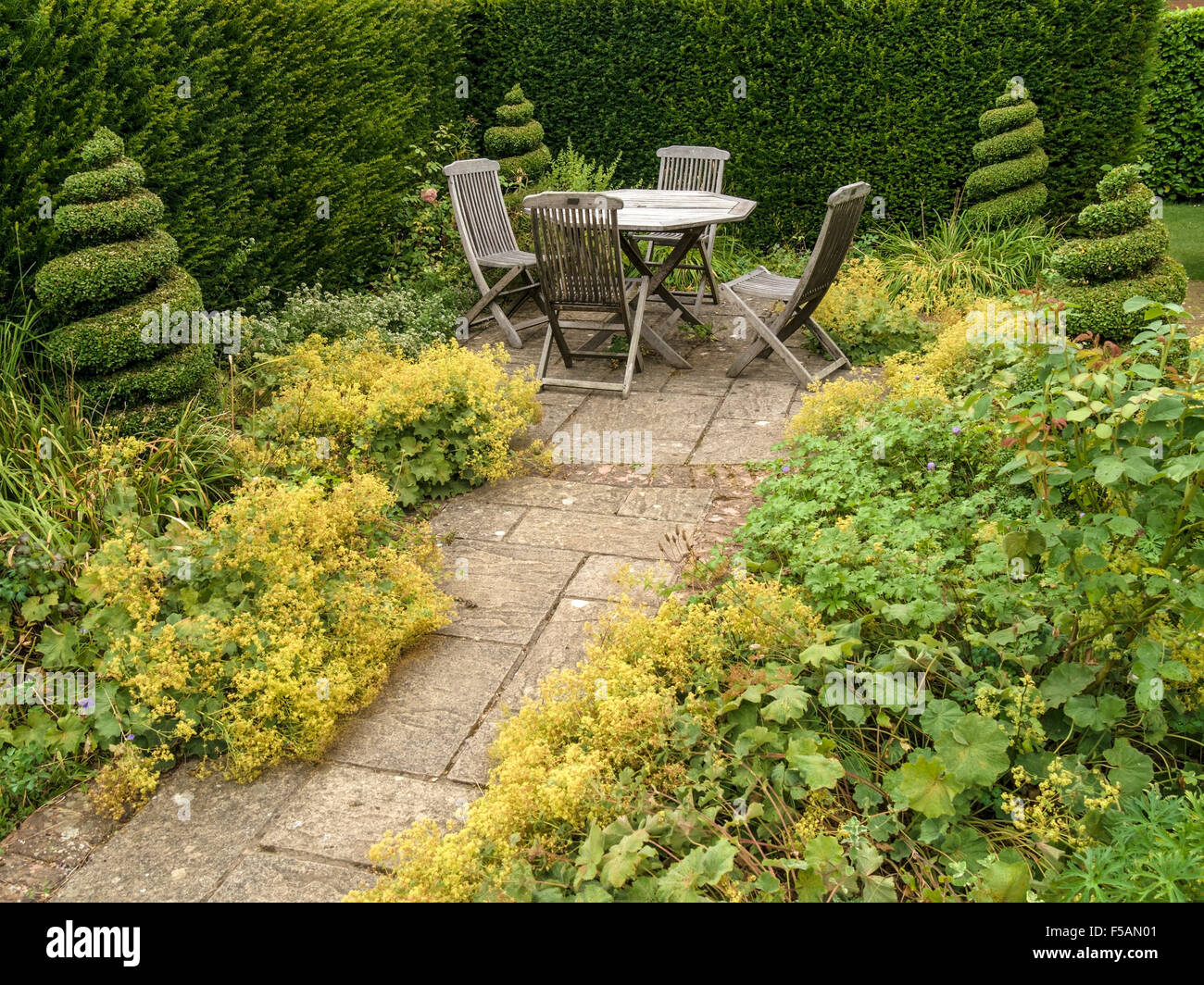Giardino patio con tavolo e 4 sedie in legno di YEW Topiaria da, Barnsdale Gardens, Rutland, Inghilterra, Regno Unito. Foto Stock
