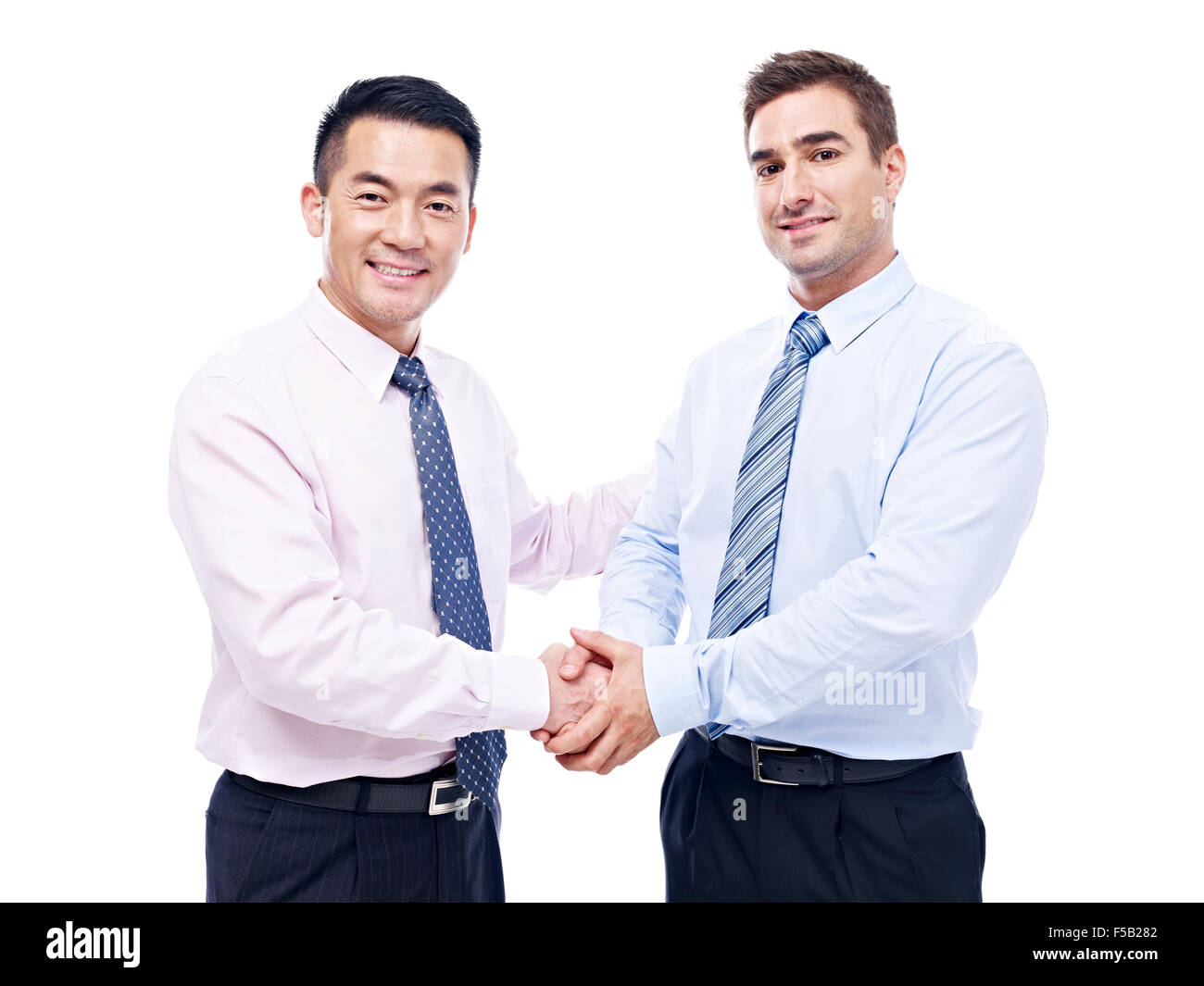 Asiatici e caucasici scuotendo gli imprenditori le mani guardando la telecamera sorridendo, isolato su sfondo bianco. Foto Stock