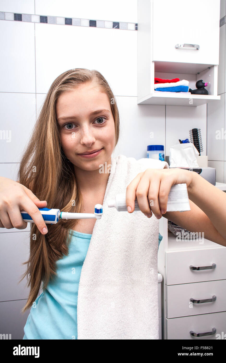La bionda ragazza adolescente spazzolare i denti in bagno Foto Stock