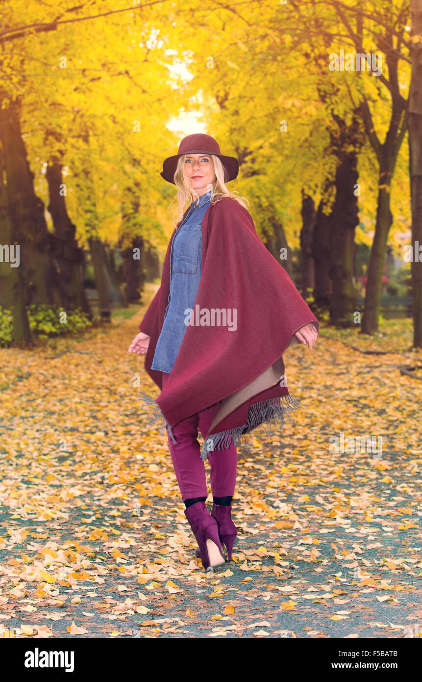 Donna bionda camminando sotto gli alberi colorati in autunno Foto Stock
