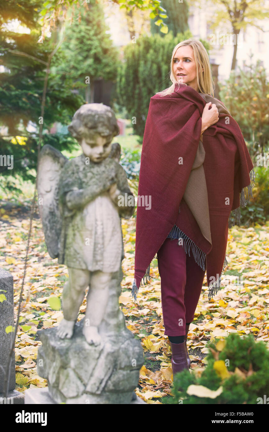 Donna che cammina nel cimitero accanto alla statua di little angel Foto Stock