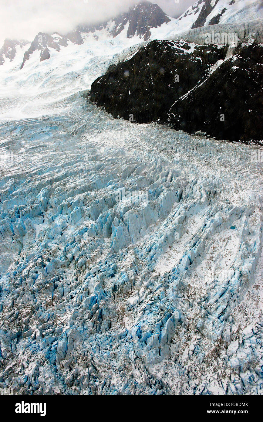 Volo sopra il ghiacciaio Fox che mostra il terreno di ghiaccio nella valle che alle pendici del Westland Tai Poutini National Park, Isola del Sud, Nuova Zelanda Foto Stock
