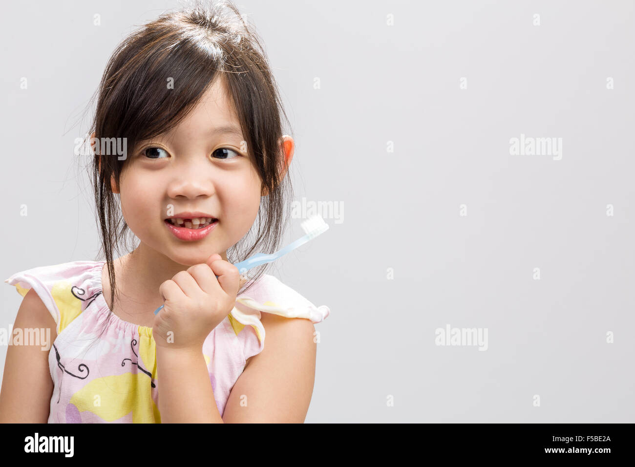 Carino ragazza asiatica la spazzolatura dei denti, studio isolato sullo sfondo bianco. Foto Stock