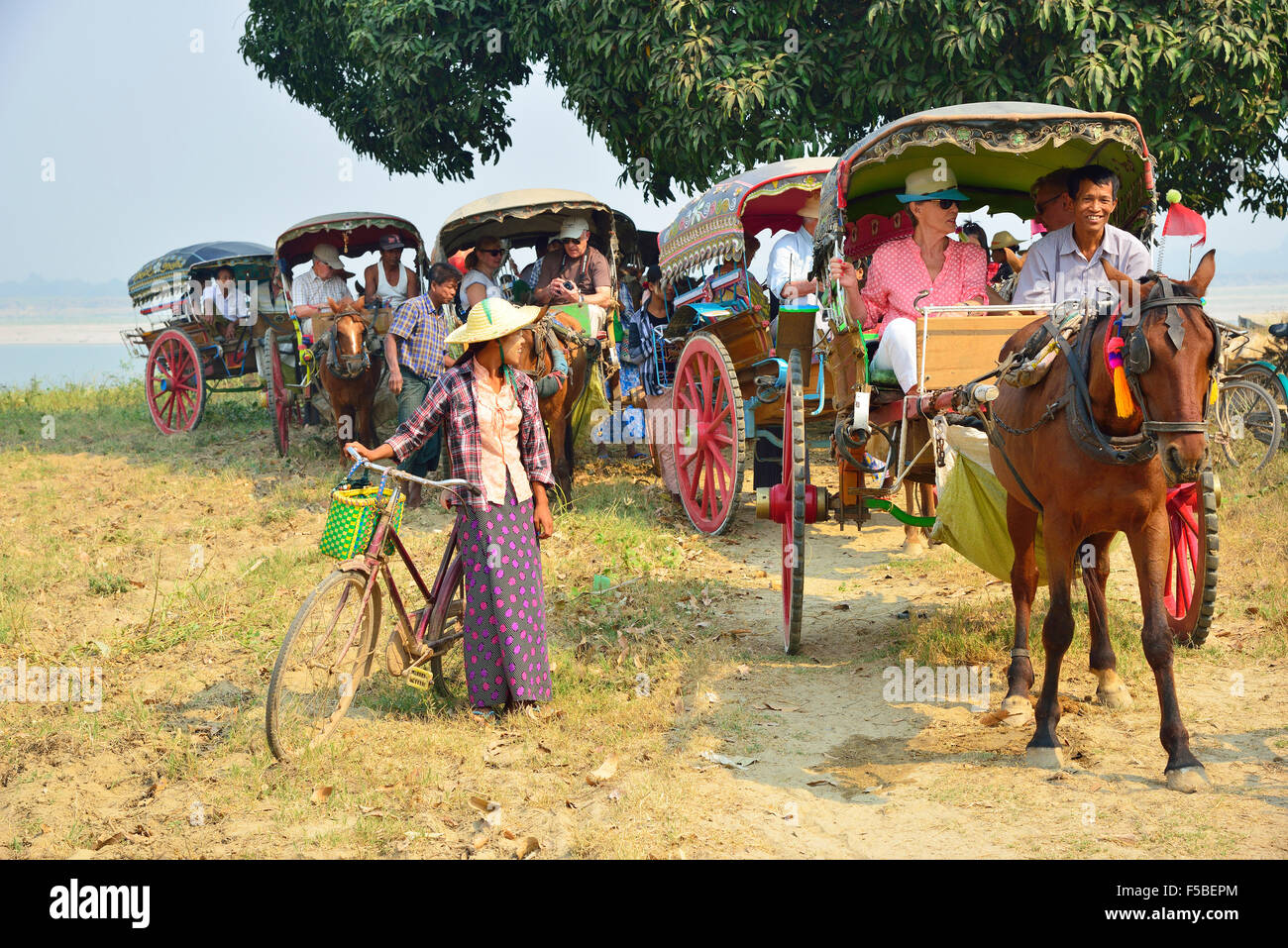 Donna locale che cerca di vendere i trinket ai turisti che escono per la giornata in carrelli a cavallo dalla loro barca da crociera Sul fiume Irrawaddy, Myanmar (Birmania) Foto Stock