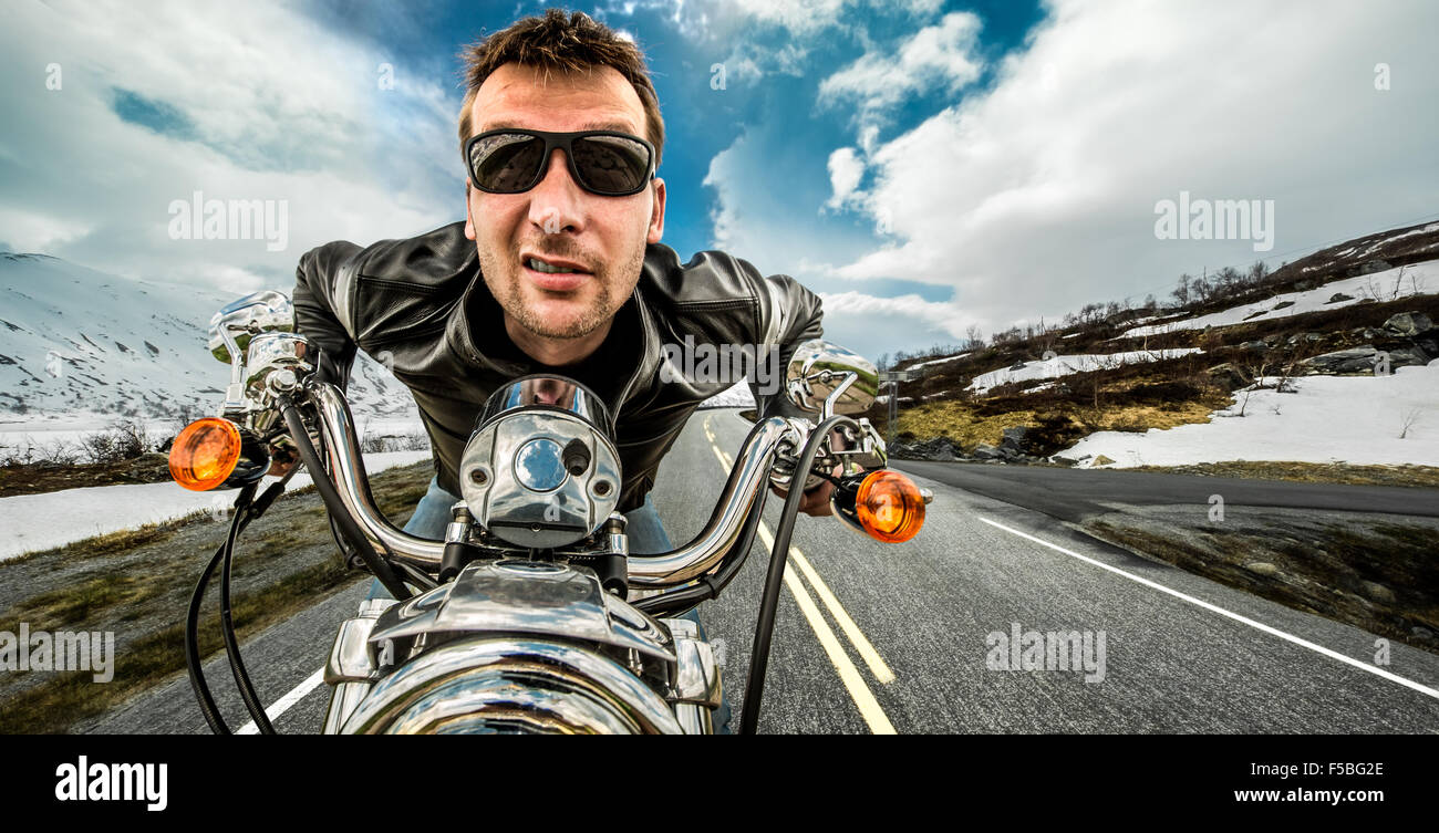 Funny Biker in occhiali da sole e giacca di pelle racing sulla serpentina di montagna. Foto Stock Funny Biker in occhiali da sole e giacca di pelle racing sulla serpentina di montagna. Foto Stock