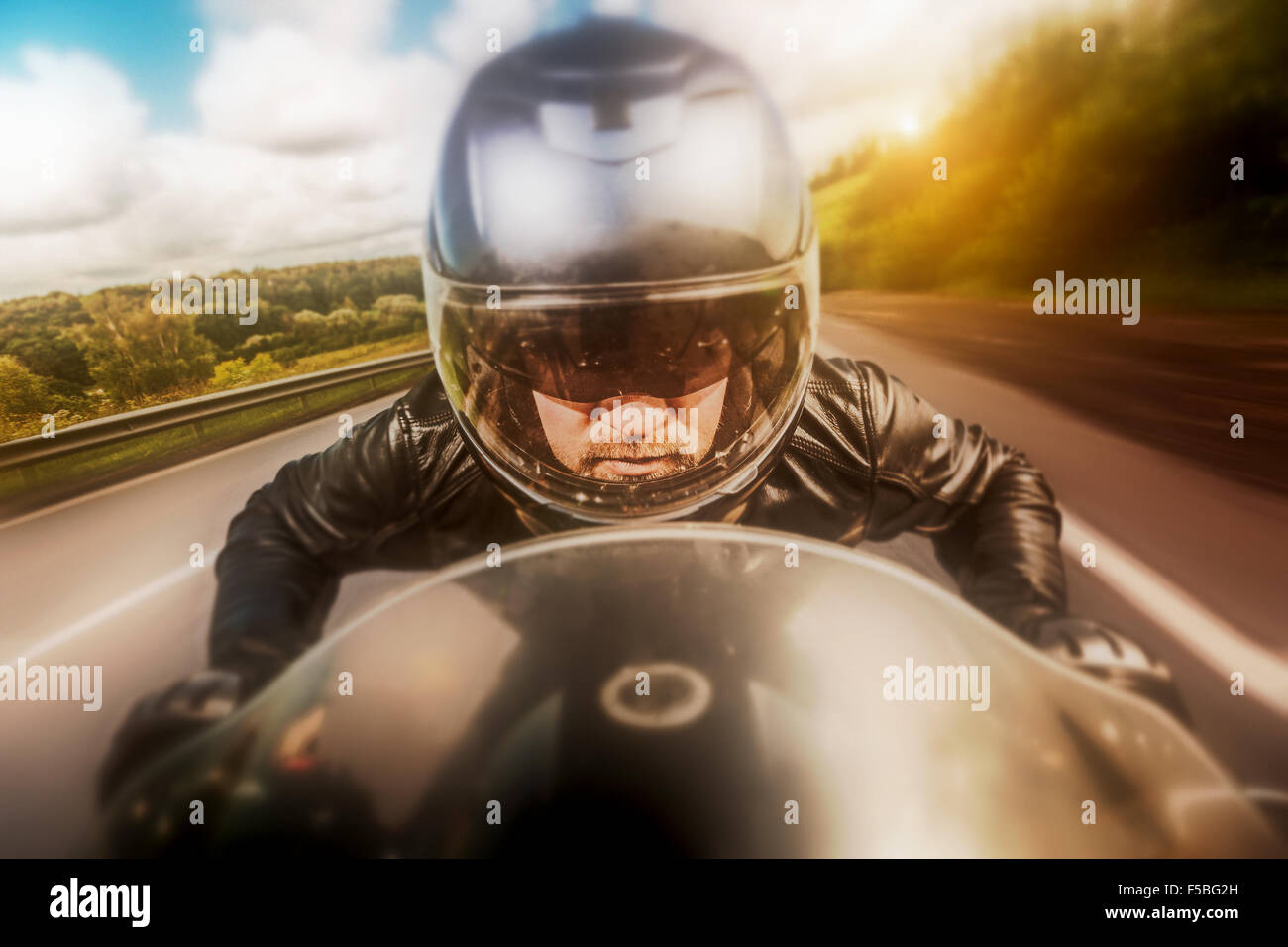 Biker in casco e giacca di pelle racing su strada. Filtro applicato in post-produzione. Foto Stock Biker in casco e giacca di pelle racing su strada. Filtro applicato in post-produzione. Foto Stock