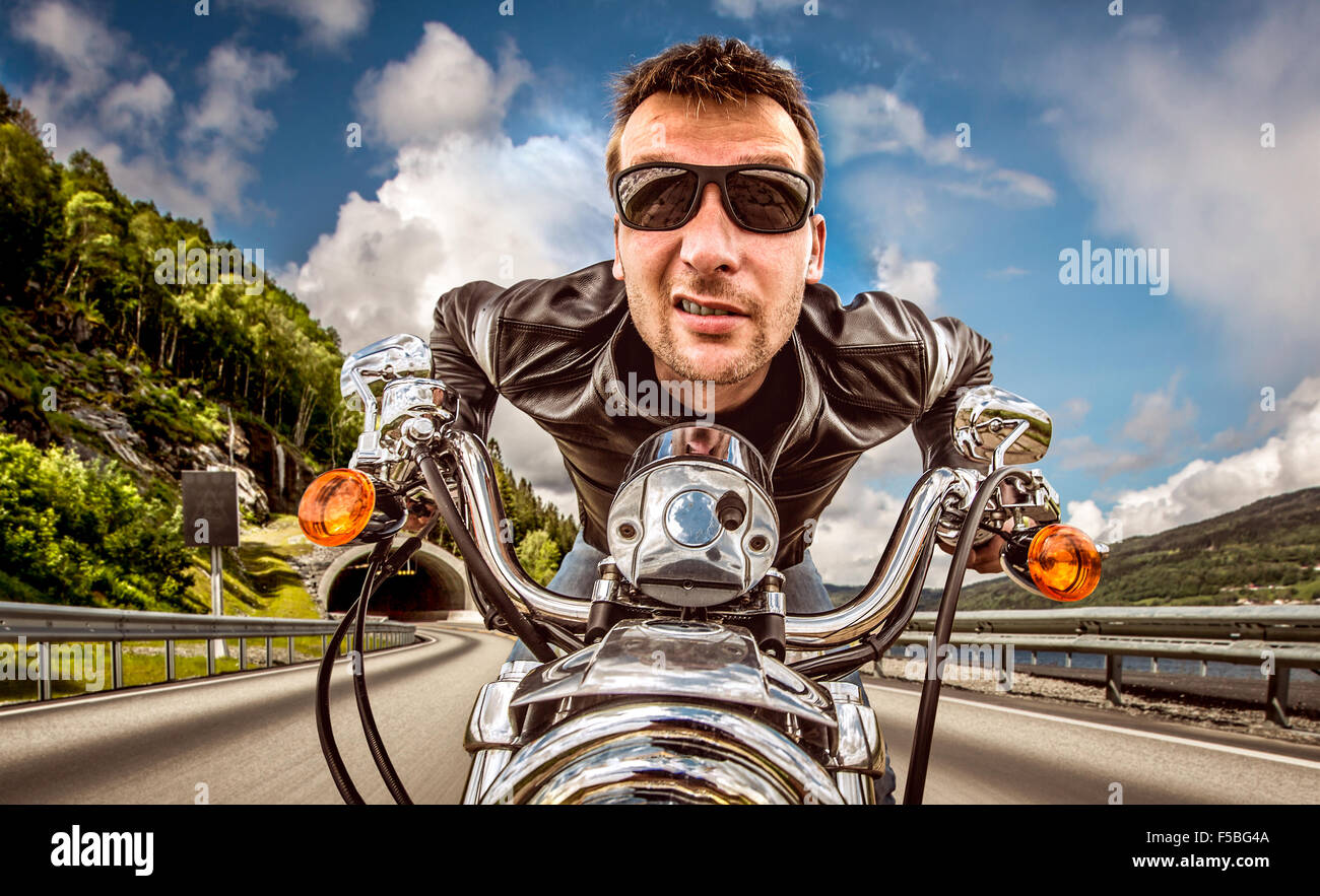 Funny Biker in occhiali da sole e giacca di pelle racing sulla serpentina di montagna. Filtro applicato in post-produzione. Foto Stock Funny Biker in occhiali da sole e giacca di pelle racing sulla serpentina di montagna. Filtro applicato in post-produzione. Foto Stock