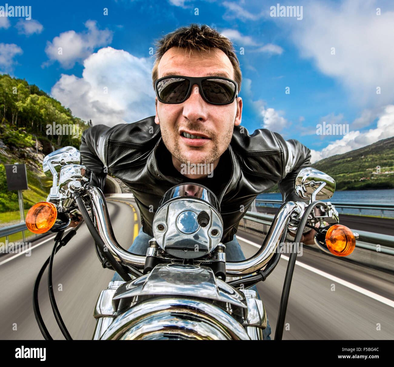 Funny Biker in occhiali da sole e giacca di pelle racing sulla serpentina di montagna. Filtro applicato in post-produzione. Foto Stock Funny Biker in occhiali da sole e giacca di pelle racing sulla serpentina di montagna. Filtro applicato in post-produzione. Foto Stock