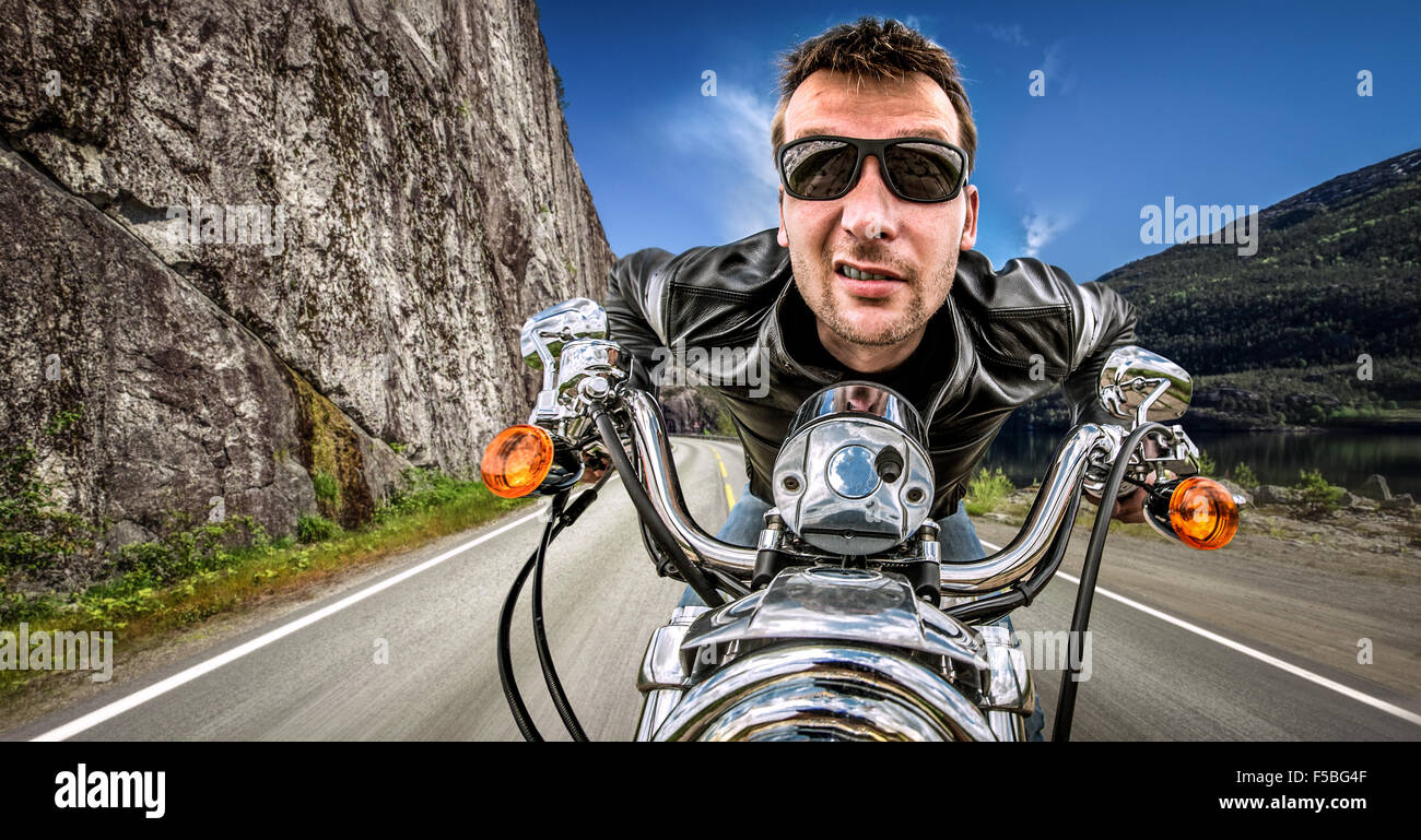 Funny Biker in occhiali da sole e giacca di pelle racing sulla serpentina di montagna. Filtro applicato in post-produzione. Foto Stock Funny Biker in occhiali da sole e giacca di pelle racing sulla serpentina di montagna. Filtro applicato in post-produzione. Foto Stock