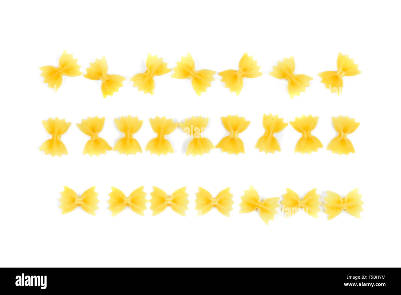 Farfalle di pasta disposte in una fila stringa su sfondo bianco Foto Stock