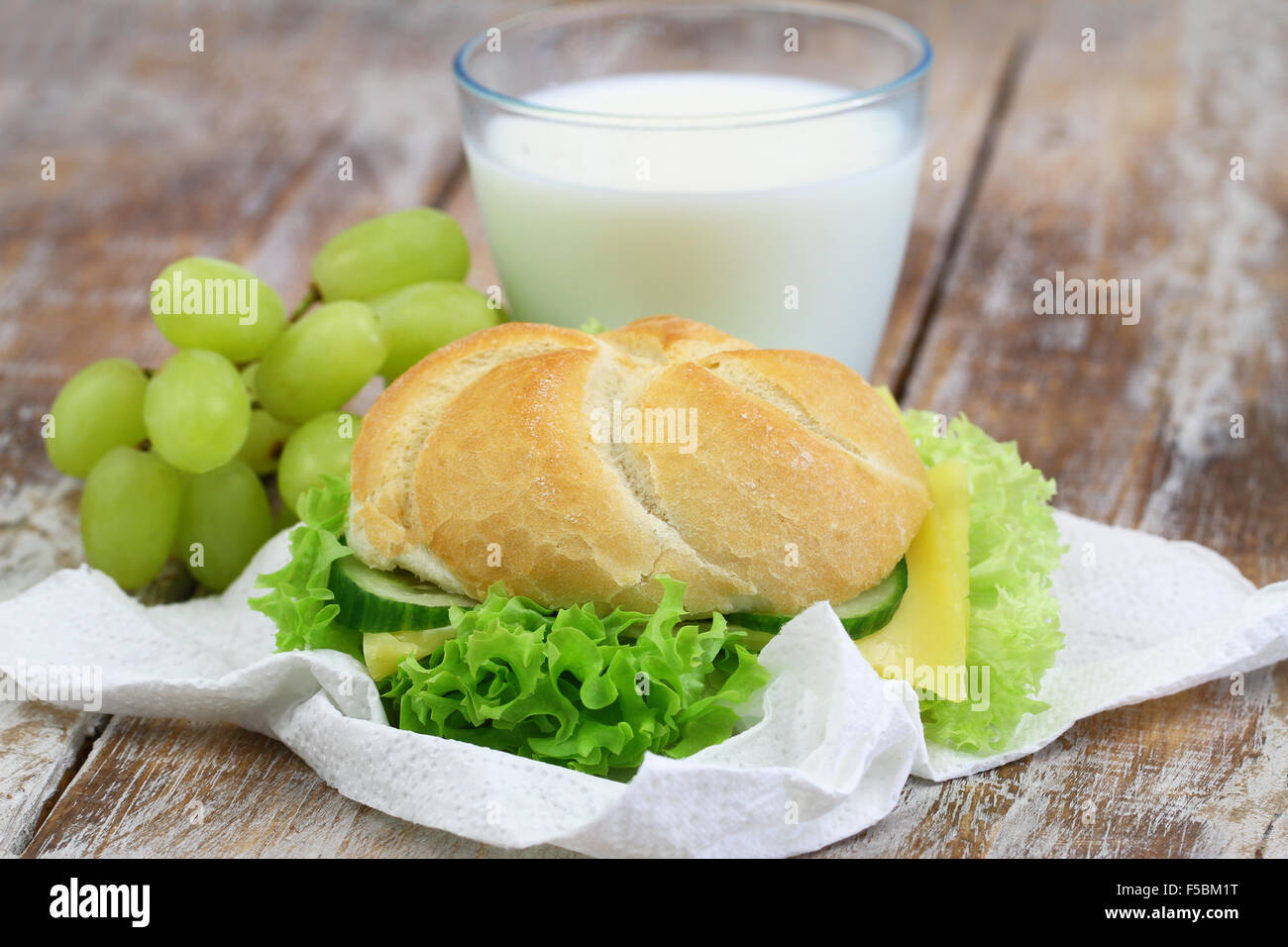 Scuola pranzo composto da rullo di formaggio, uva e bicchiere di latte Foto Stock