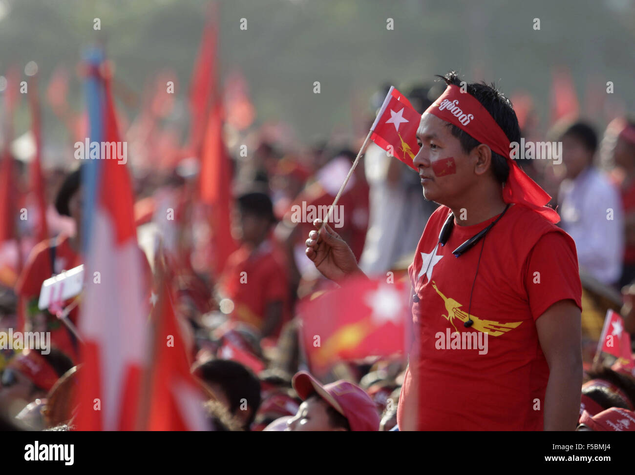 Yangon, Myanmar. 1 Nov, 2015. Un uomo tiene una bandiera della Lega nazionale per la democrazia (NLD) di Aung San Suu Kyi, presidente della NLD, offre una campagna discorso a Yangon, Myanmar, nov. 1, 2015. Campaignings dai principali partiti politici in Myanmar intensificato la domenica come nov. 8 elezione generale è entrato in sette giorni di conto alla rovescia. Credito: U Aung/Xinhua/Alamy Live News Foto Stock