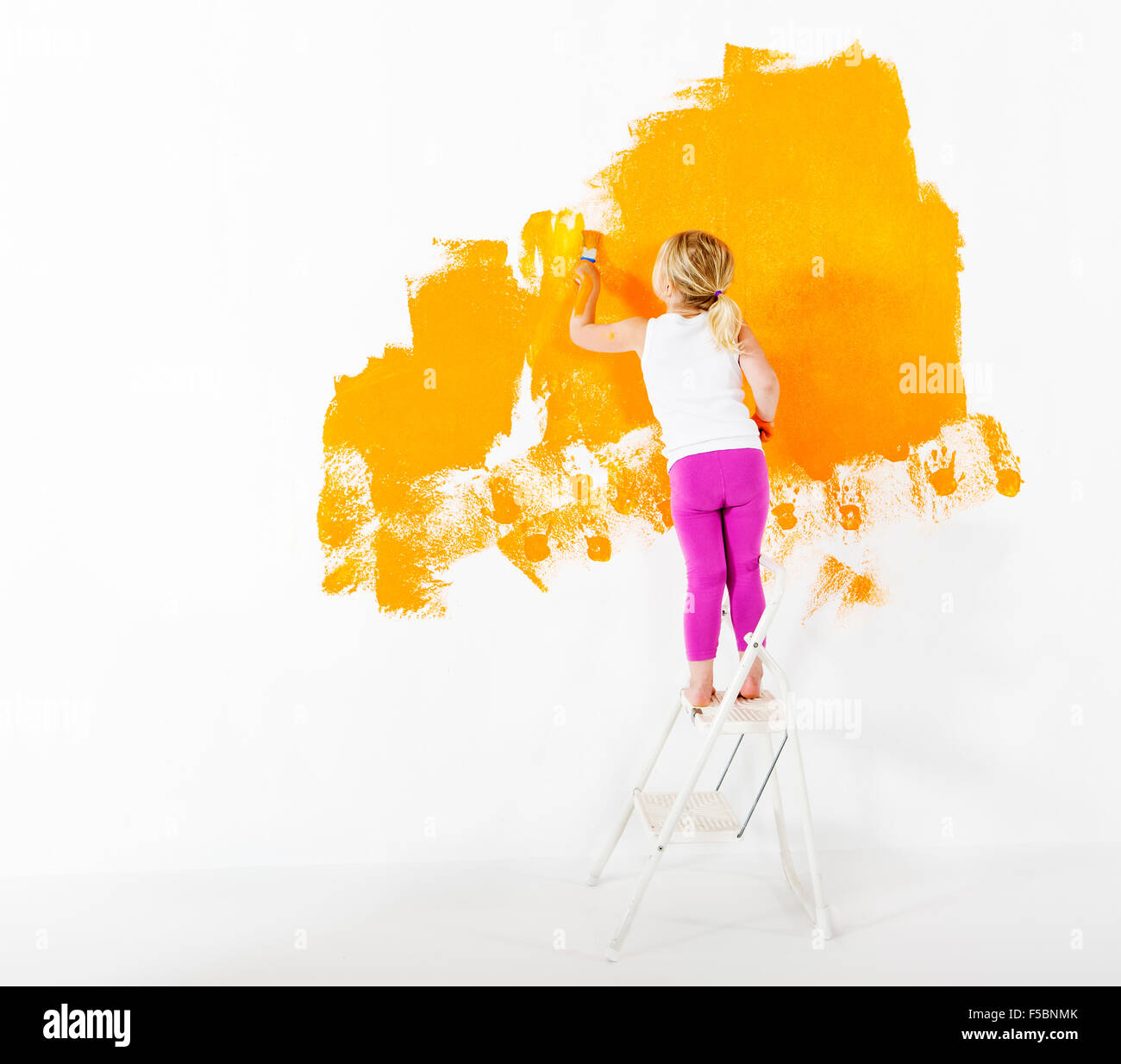 Bambina pittura muro bianco con colore arancio Foto Stock