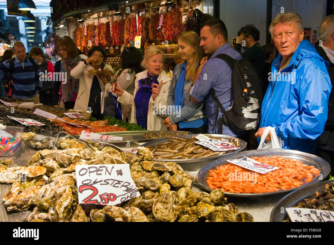 Turisti che mangiano ostriche su crostacei e frutti di mare stalla a Los Angeles Boqueria mercato Las Ramblas Barcellona Catalonia Spagna ES Foto Stock