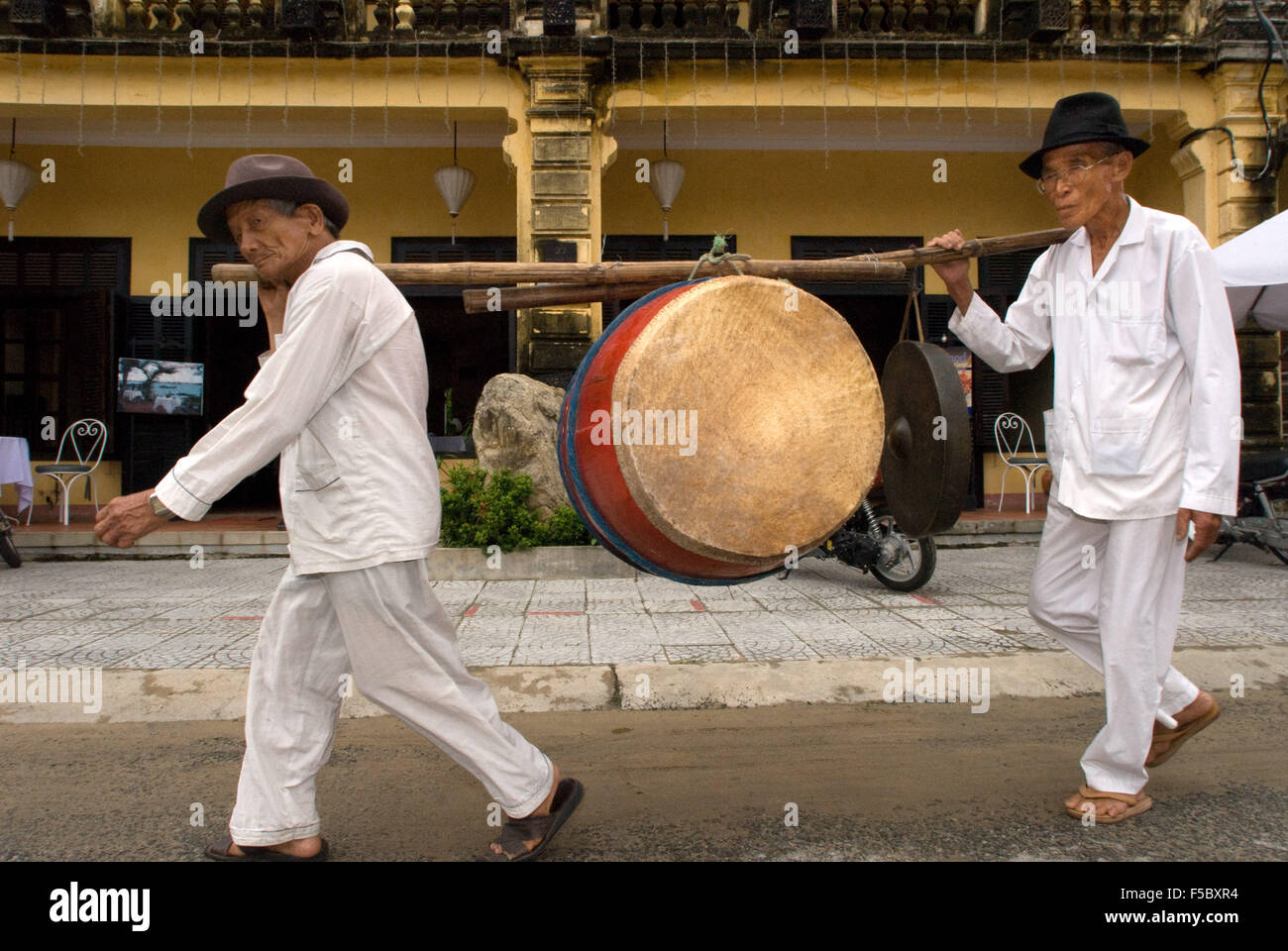 Musicisti con bass drum, Hoi An, Vietnam. Scena di strada / edificio fronte Shop / Arcitecture tradizionali, Hoi An, Vietnam. Quang Foto Stock