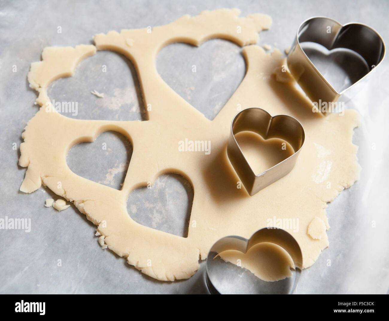 Heart-Shaped cookie cutter e pasta biscotto sulla carta oleata Foto Stock