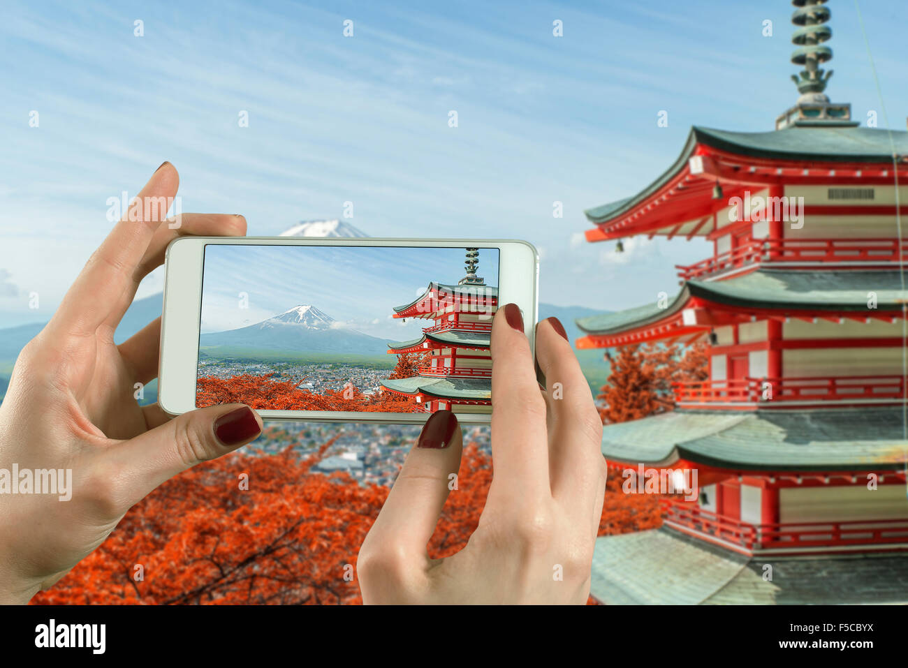 Vista posteriore di una donna prendendo fotografia con uno smart phone fotocamera a Mt. Fuji con i colori dell'Autunno in Giappone. Foto Stock