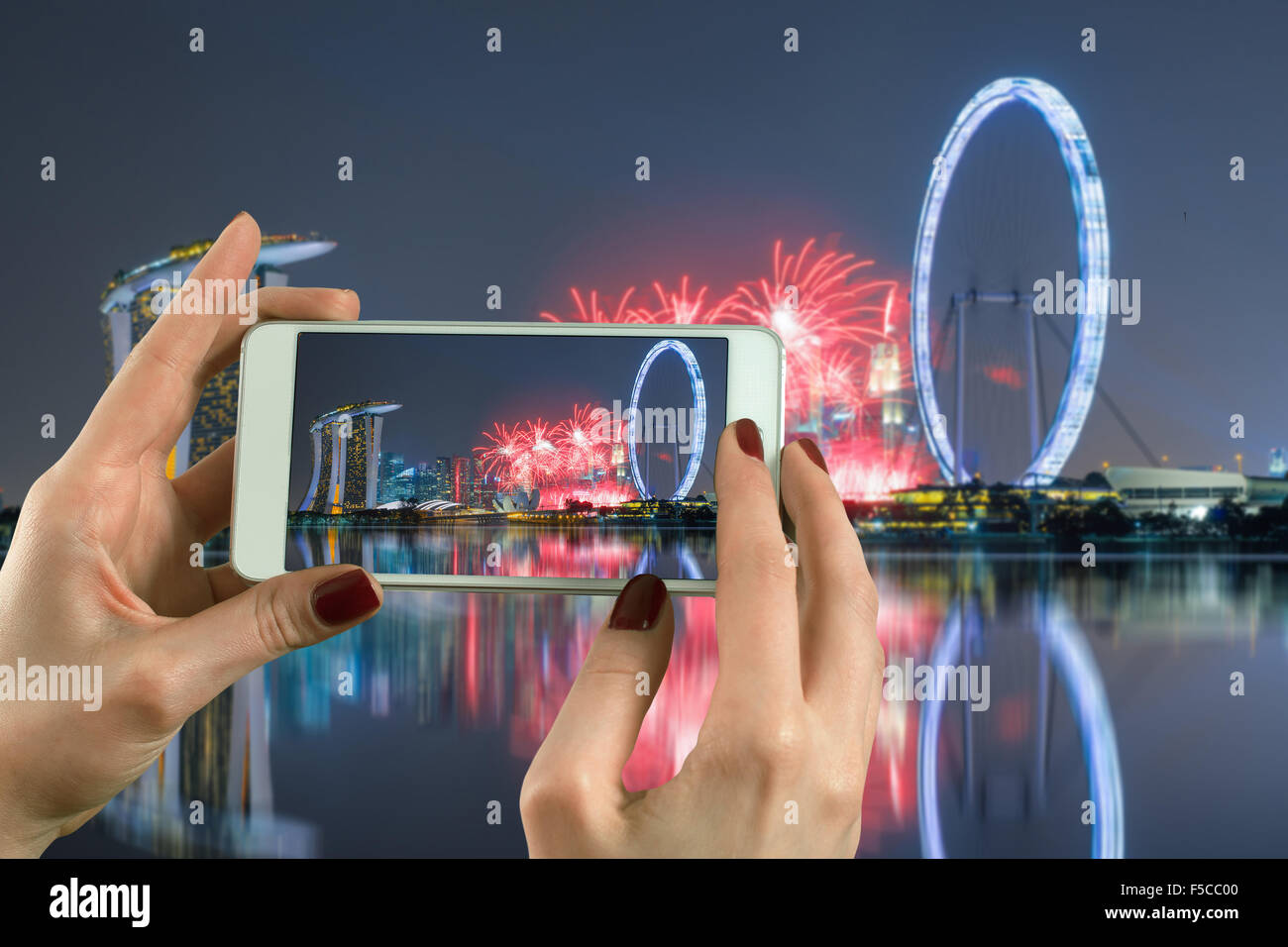 Vista posteriore di una donna prendendo fotografia con uno smart phone fotocamera di Marina Bay a Singapore Foto Stock
