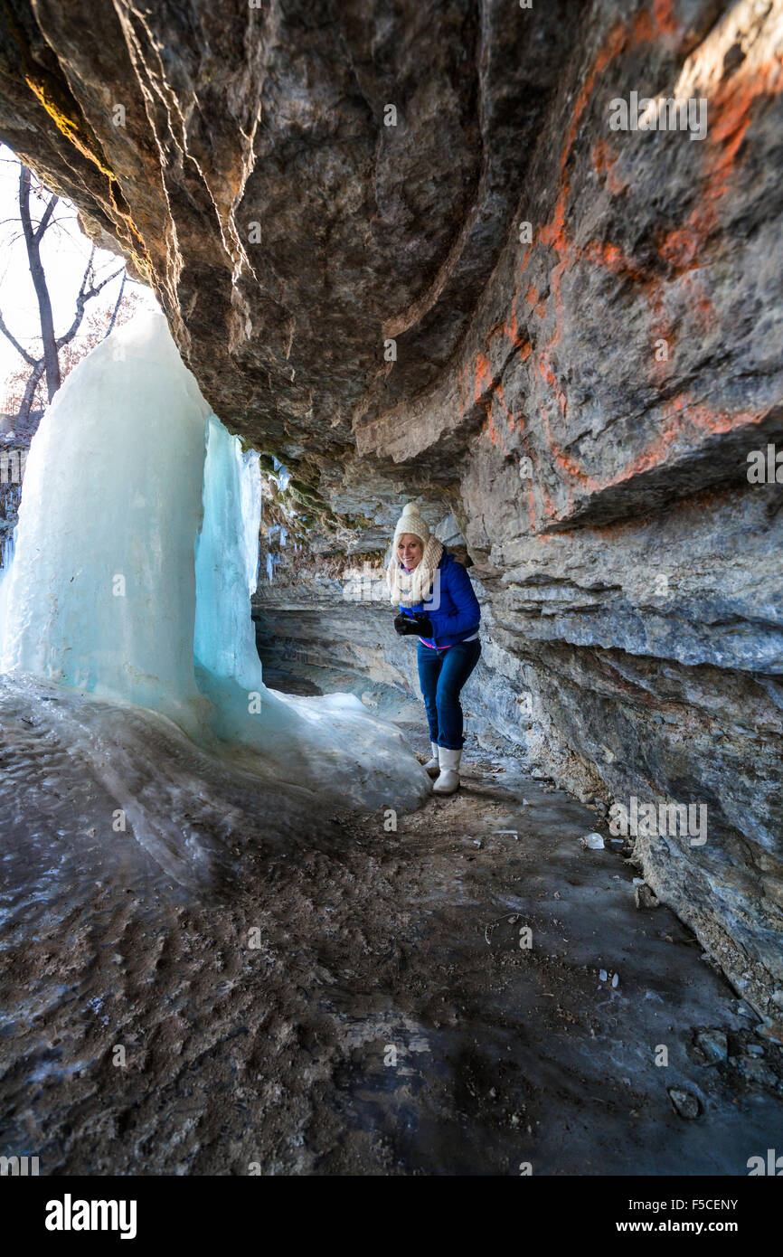 Caucasian donna in abiti invernali esplora dietro congelati cascate Minnehaha in inverno, Minneapolis, MN, Stati Uniti d'America Foto Stock