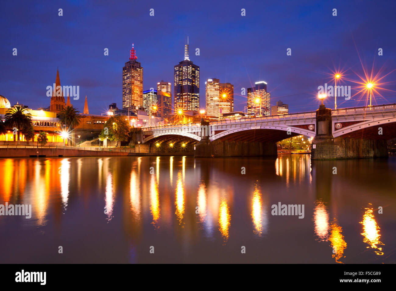 Lo skyline di Melbourne in Australia con la stazione di Flinders Street e i capi da ponte attraverso il fiume Yarra di notte. Foto Stock