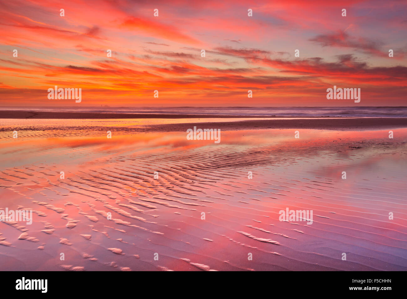 Bel tramonto e riflessioni sulla spiaggia con la bassa marea. Foto Stock