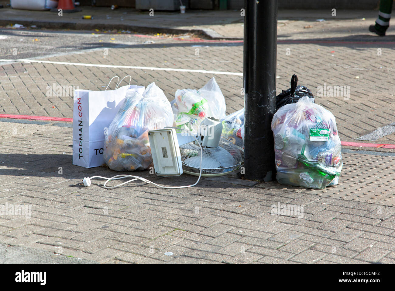 Bin di sacchetti e rifiuti sinistra sul mio un palo sul marciapiede, London, Regno Unito Foto Stock