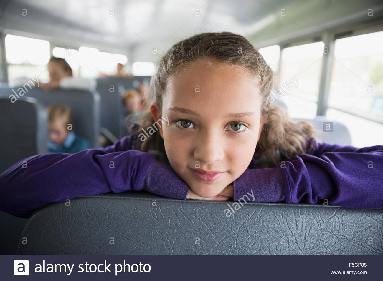 Close up ritratto grave schoolgirl su bus di scuola Foto Stock